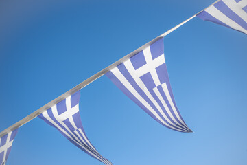 Traditional Greek Bunting Flags Waving Against a Clear Blue Sky During a National Celebration