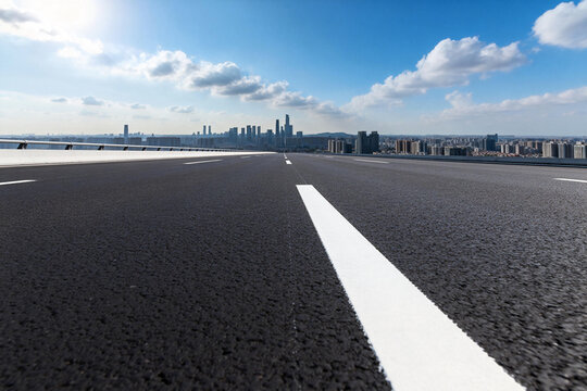 Asphalt Road Leading to Urban Skyline Under Blue Sky