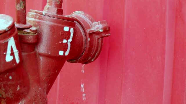 Fire hydrant outlet drips water with visible drop forming under metal cap.
