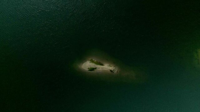 Top view to island in middle of lake, aerial view of island isolated in middle of serene lake. pristine minimalistic oasis creating focus and isolation themes