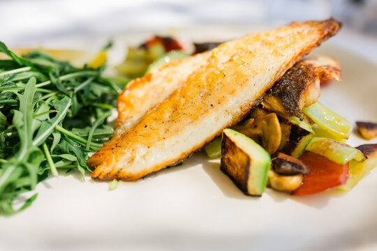 Grilled fish fillet with vegetables served on restaurant plate. Healthy nutrition, balanced diet choices and mindful dining habits supporting modern lifestyle wellbeing.