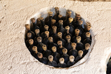 Top view of dusty vintage wine bottles stored in a stone cellar, showcasing aged corks and textured surfaces for a rustic, authentic look.