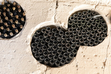 Rows of dusty vintage wine bottles stored horizontally in circular stone cellar niches, emphasizing tradition, aging, and rustic textures.