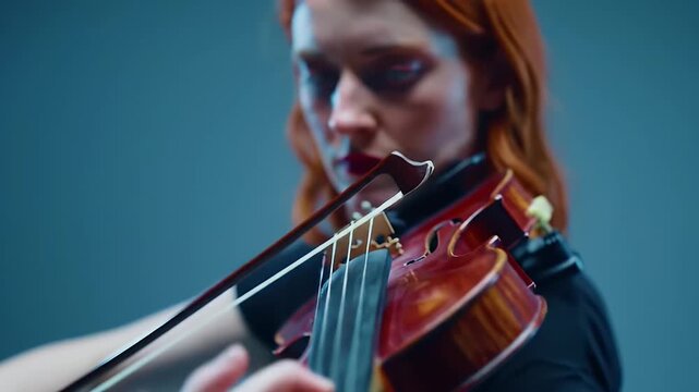 Focused redhead musician passionately playing the violin in a dimly lit environment