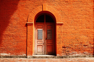 Arched Wooden Door with Red Clay Brick Frame on Light Orange Background.