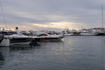 Modern marina in Athens, Greece with luxury yachts lined along the pier. Calm harbor water, sleek hulls and cloudy sky form a clean maritime travel scene.