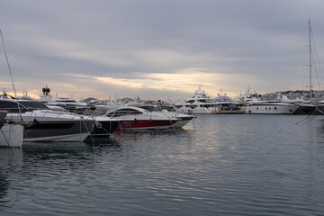 Modern marina in Athens, Greece with luxury yachts lined along the pier. Calm harbor water, sleek hulls and cloudy sky form a clean maritime travel scene.