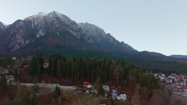Aerial drone footage of Busteni town with the Caraiman Mountains in the background, filmed in winter daylight. 