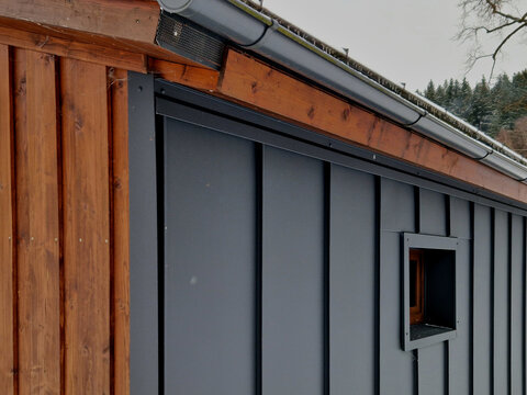The dark panels are a style called Standing Seam Metal Siding, which is popular for its sleek lines and durability.Modern Cabin or Scandinavian architecture.