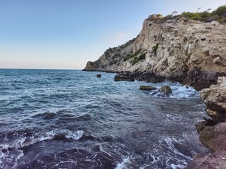 Fototapeta premium calm sea with rocky shoreline, peaceful coastal landscape with gentle ripples and warm sunlight