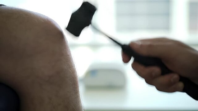 Medical examination of a patients knee using a reflex hammer for diagnosis.