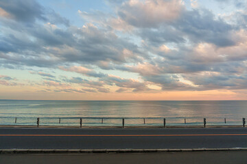 Scenic asphalt coastal road with the sea and colorful evening sky as the background.
