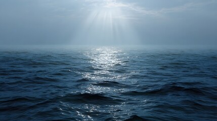 Sunlight streams through atmospheric clouds illuminating the vast rippling ocean surface with radiant beams