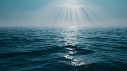 A calm ocean surface bathed in atmospheric sun rays filtering through clouds and haze