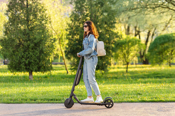Young woman riding electric scooter in park, eco transport, sustainable urban lifestyle, green city.