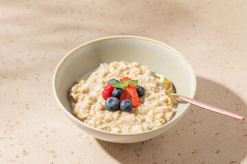 Tasty oatmeal porridge with strawberries, raspberry, blueberries in bowl. Healthy breakfast