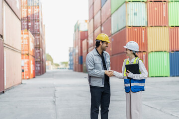 professional male and female industrial worker shaking hands and smiling at a cargo container terminal, representing a successful business deal and collaboration in logistics.