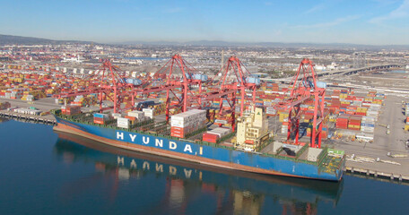 AERIAL: Cranes move shipping containers from docks and onto massive cargo ship