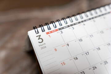 A close-up view of a calendar page flipped to March 2026, featuring dates, numbers, and days of the...