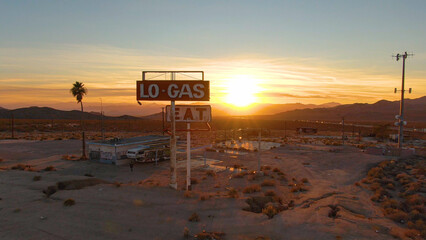 AERIAL: Unrecognizable photographer explores abandoned fuel station at sunset.
