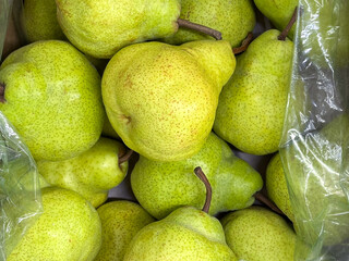 Pile of fresh green pears in a box, close-up view