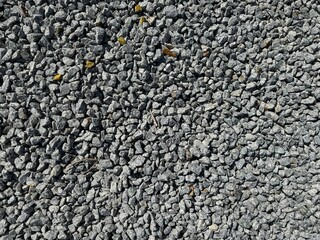 Close-up of gray gravel stones forming a rough natural texture, ideal for construction, landscaping, industrial backgrounds, or abstract design with a realistic rocky surface.