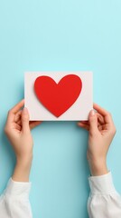 Hands holding red heart card on blue background image