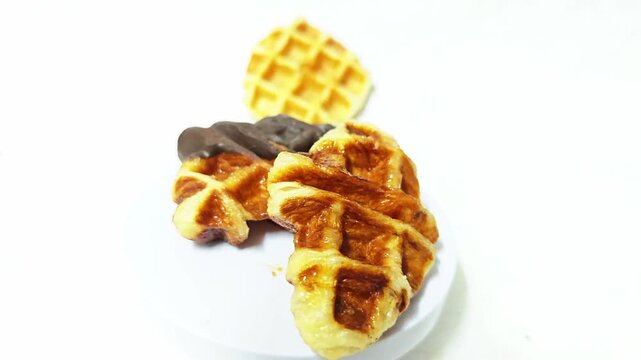 Close-up of golden-brown Li&egrave;ge waffles with caramelized sugar pearls on a white background, highlighting the crispy texture.