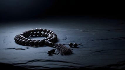 Dark still life of prayer beads on stone surface, minimal spiritual composition
