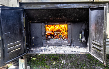 Field kitchen for cooking camp food. Bright fire burns in the stove of a field kitchen