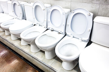 Assortment of ceramic toilet bowls are located in a plumbing store