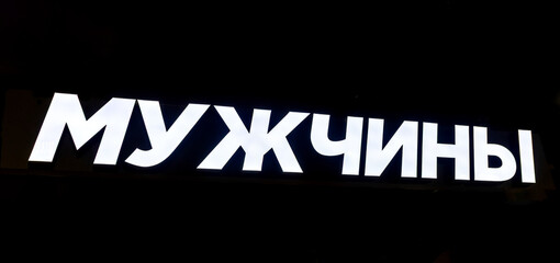 Glowing signboard on a black background. Text in Russian: Men