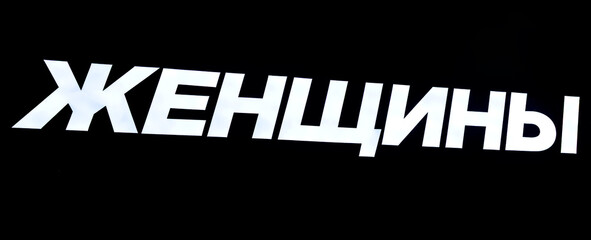 Glowing signboard on a black background. Text in Russian: Women
