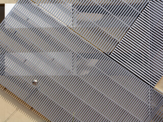Building exterior wall facade with aluminium cladding in diagonal repetitive pattern in silver grey. and a wall street light.
