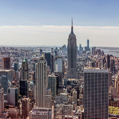 Empire state building dominating new york city skyline on sunny day