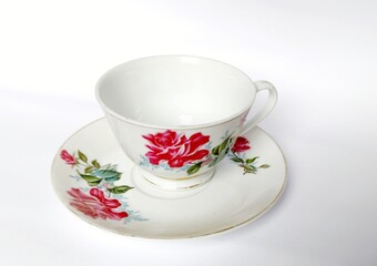 Fototapeta premium White tea cup and saucer with red floral pattern on a plain background.