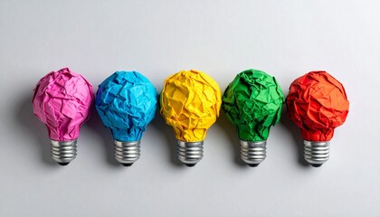 Creative concept of ideas shown as colorful crumpled paper shaped like light bulbs on bases, against a light gray background.