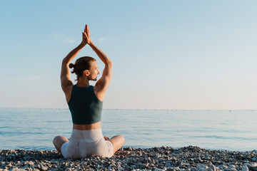 Woman meditating and breathing at seaside at sunset or sunrise. Holistic Health and Mental Well-Being.