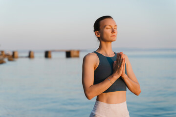 Woman meditating and breathing at seaside at sunset or sunrise. Holistic Health and Mental Well-Being.