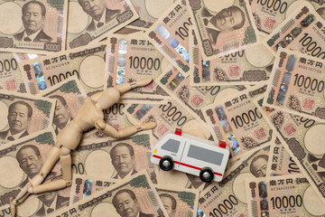 倒れた人形と救急車と敷き詰められた一万円札