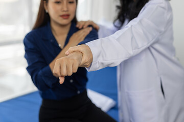 Female doctor examining the arm of a young female patient during a medical consultation in a...
