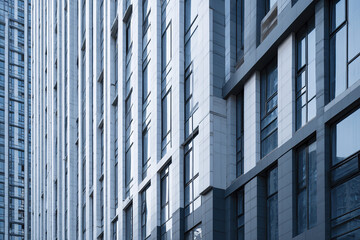 High rise curtain wall detail narrow vertical window strips on modern building facade with reflective glass panels in cool tones