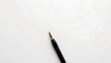 A pen resting on top of a piece of paper. The pen has a black ink nib and is positioned in the upper right corner of the frame. The paper appears to be a light color, possibly white or cream