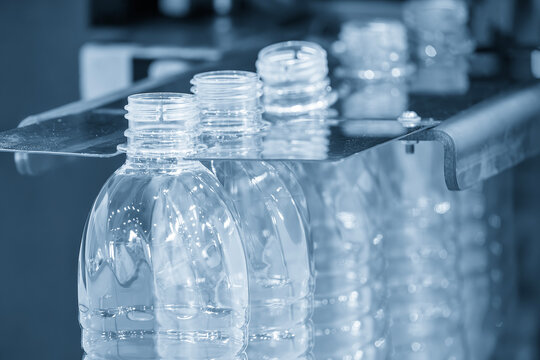 The  empty drinking water bottles  on the conveyor belt for filling process in the light blue scene.