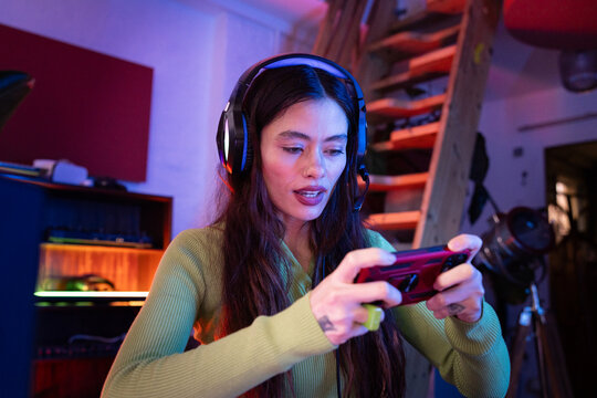 Female Gamer Excitedly Using Mobile Device and Headset