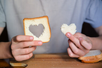 Man's hands holding bread. Slice of toast, whole grain bread. Heart, love, Valentine's Day, positive emotions, joy, delicious breakfast for kids.