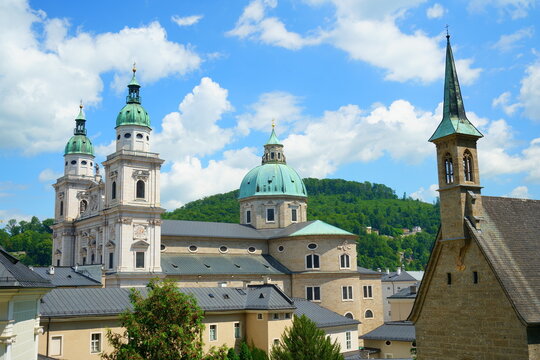 Low-angle view of the Salzburg Cathedral (Salzburger Dom) showcasing its iconic turquoise domes and early Baroque architecture against a clear blue sky in Salzburg, Austria
