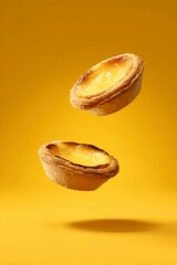 two egg tarts floating in the air, yellow background