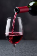 wine bottle pouring red wine into a glass on a black background.