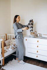 Woman mother checking and folding cloths at kids room